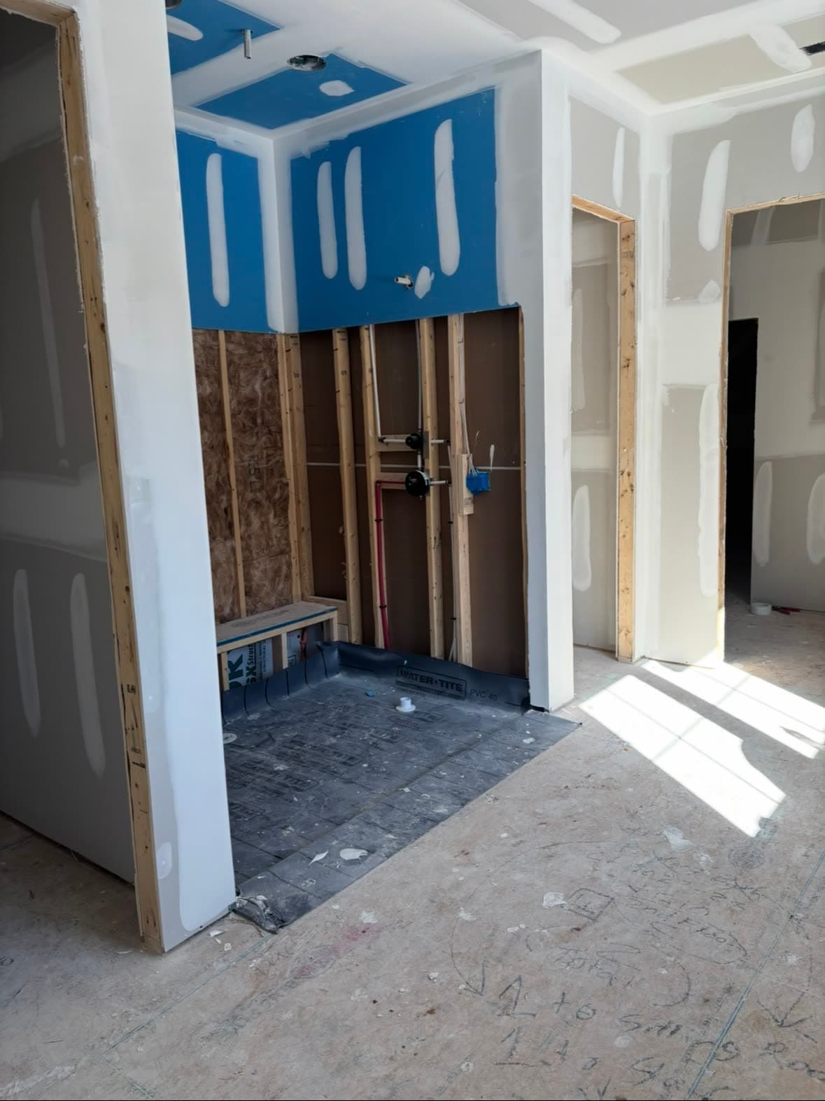Master shower rough-in with stud walls and waterproofing — before