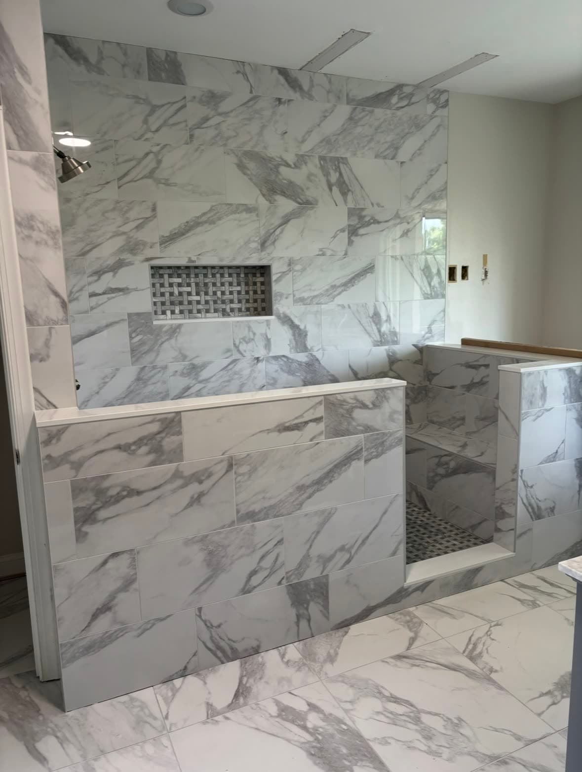 Finished marble shower with woven mosaic niche and tile bench — after