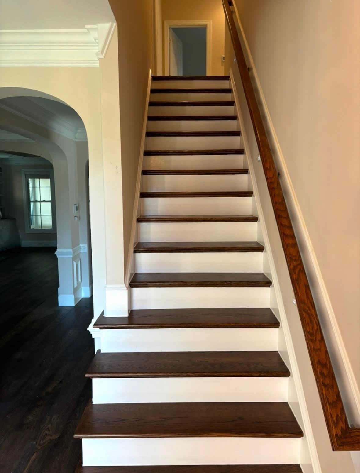 Refinished oak staircase with dark-stained treads, dark hardwood floor, and white risers